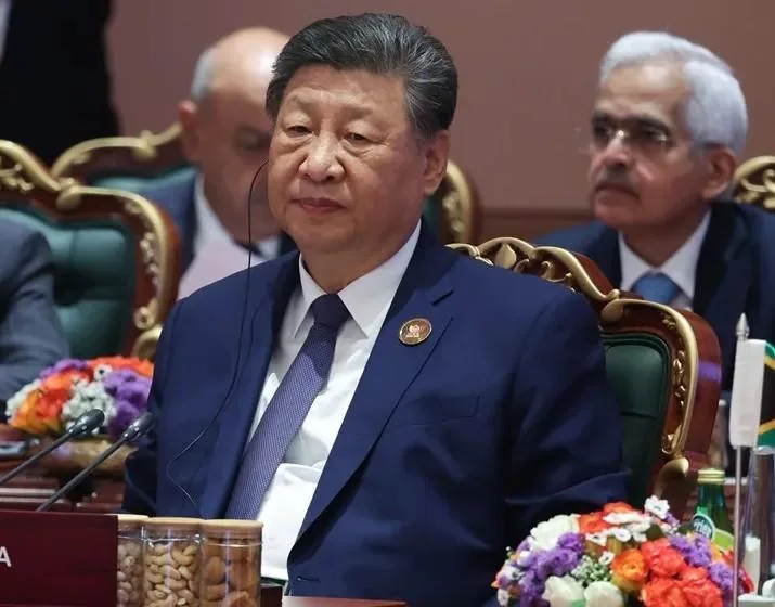Xi Jinping en una mesa de conferencia luciendo traje azul marino y audífono durante una cumbre.