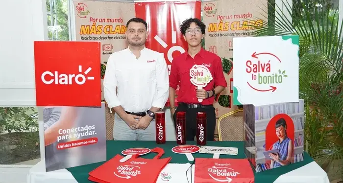Dos hombres jóvenes posan junto a una mesa con material promocional de Claro y la campaña de reciclaje Salvá lo bonito.