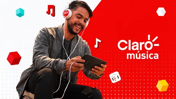 Hombre sonriente con auriculares Claro música y tablet, disfrutando contenido digital. Fondo rojo con logo Claro música y notas musicales.