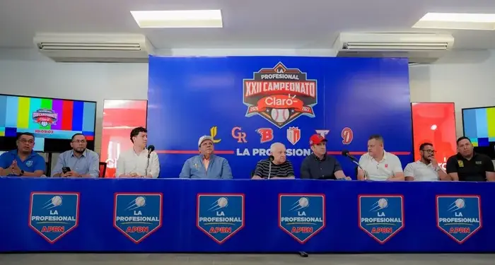 Grupo de hombres sentados en una mesa con micrófonos frente a un fondo azul con el logo del XXII Campeonato.