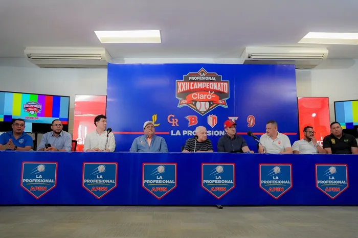 Grupo de hombres sentados en una mesa con micrófonos frente a un fondo azul con el logo del XXII Campeonato.