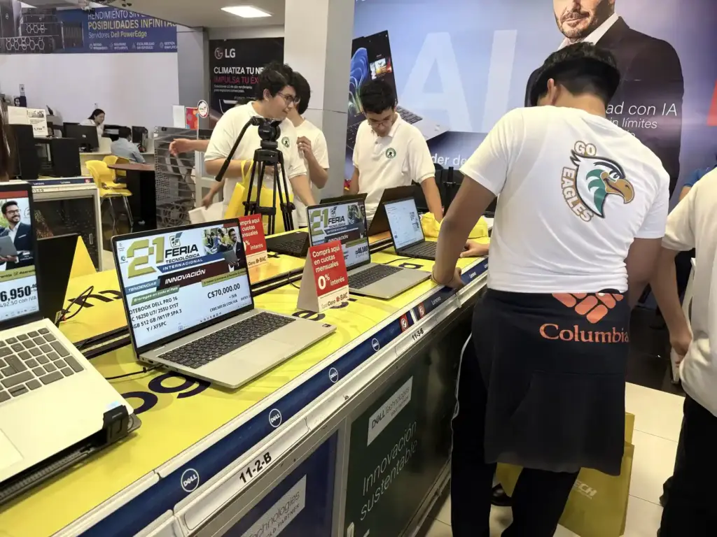 Jóvenes prueban laptops Dell y Lenovo con carteles de la 21 Feria Tecnológica Internacional de Comtech