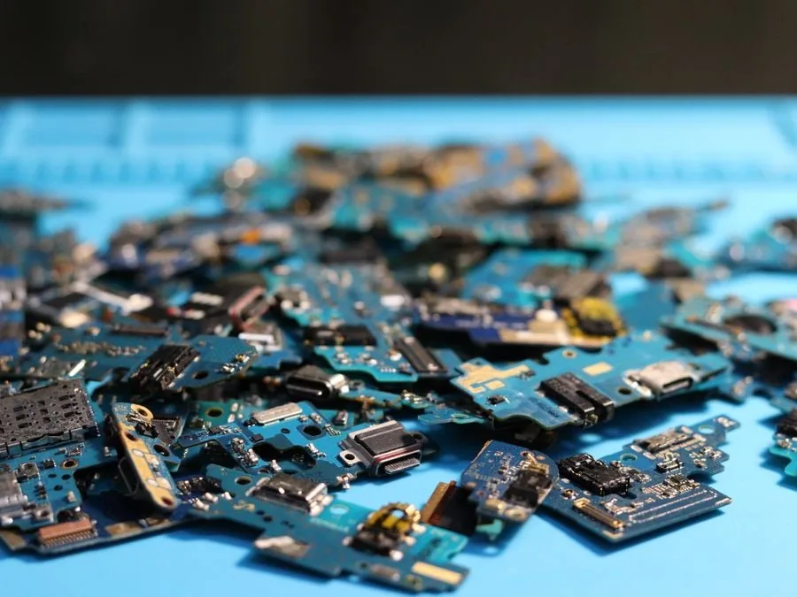 Montón de placas base y componentes electrónicos sobre una superficie azul para reciclaje.