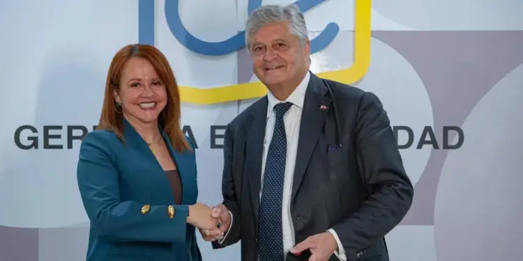 Dos profesionales, un hombre y una mujer, se dan la mano sonriendo en un entorno de negocios. Fondo con logo azul y amarillo.