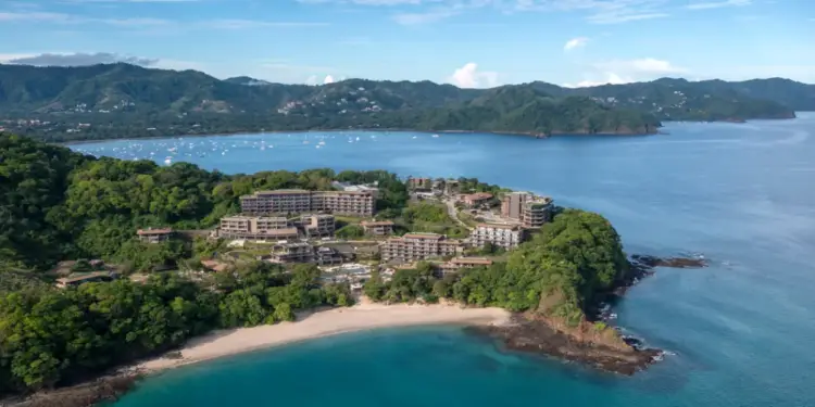 Vista aérea de un complejo hotelero moderno ubicado en una península junto a la playa y el mar.