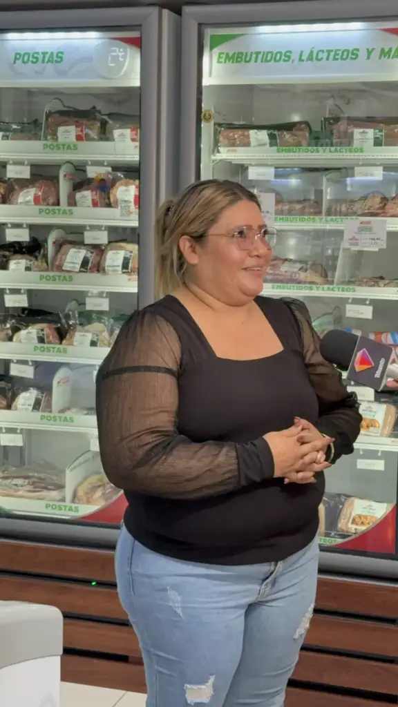Ganadora de la promoción Comprá y Ganá conversa con la prensa frente a las vitrinas de postas y embutidos de una Tienda Distrito Carnic