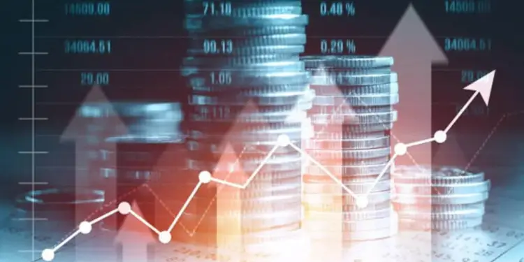 Pilas de monedas apiladas con gráficos financieros y flechas de tendencia alcista en tonos azules y rojos.