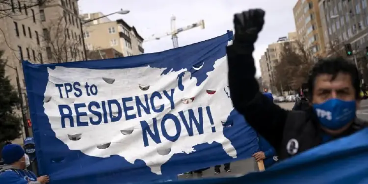 Manifestantes sostienen una pancarta con el mapa de Estados Unidos que dice 'TPS to RESIDENCY NOW!' (TPS a Residencia ¡YA!), exigiendo cambios en la política migratoria.