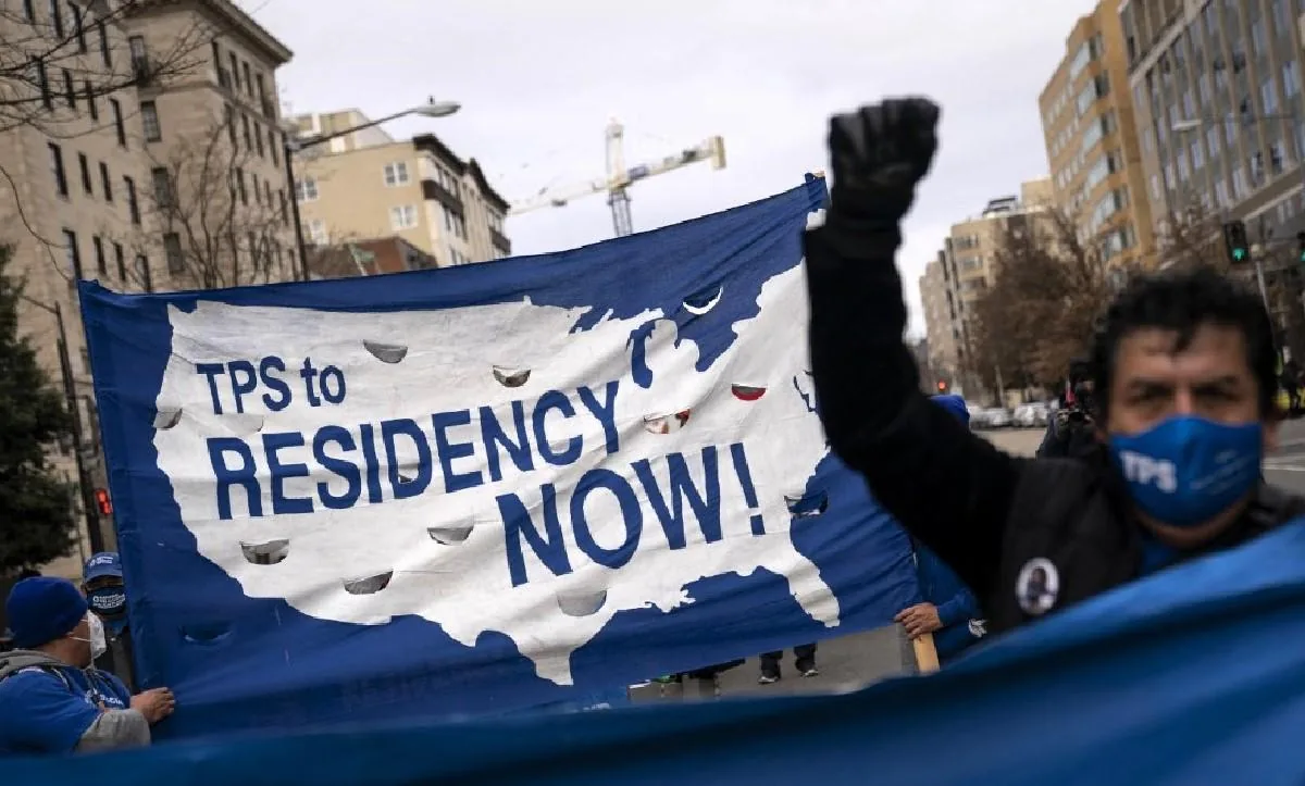 Manifestantes sostienen una pancarta con el mapa de Estados Unidos que dice 'TPS to RESIDENCY NOW!' (TPS a Residencia ¡YA!), exigiendo cambios en la política migratoria.