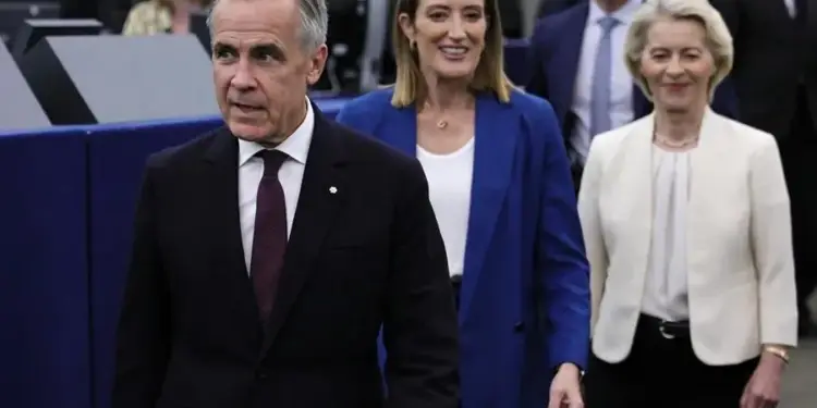 Tres profesionales, un hombre y dos mujeres, caminan en un entorno institucional. El hombre viste traje oscuro, las mujeres blazers.