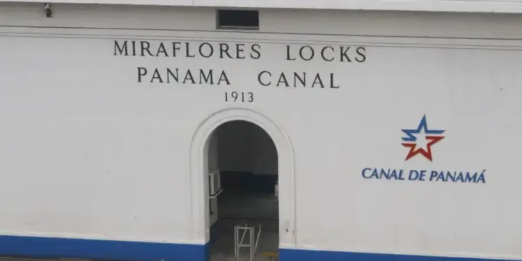 Fachada blanca de un edificio de las esclusas de Miraflores con el texto Canal de Panamá y un logotipo de estrella azul y roja.