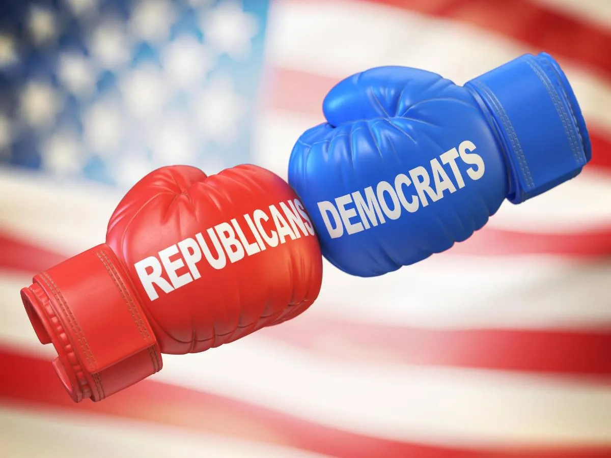 Guantes de boxeo rojo y azul con las inscripciones REPUBLICANS y DEMOCRATS sobre fondo de la bandera de Estados Unidos.
