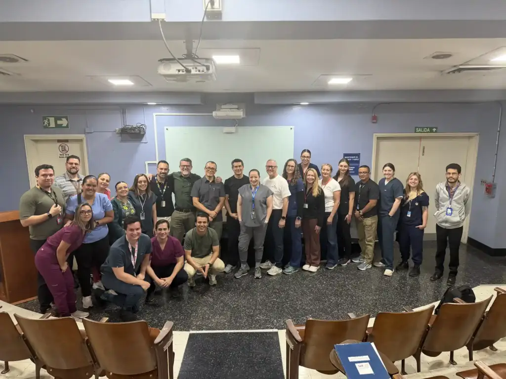 Amplio grupo de hombres y mujeres profesionales sonriendo juntos en un auditorio corporativo.