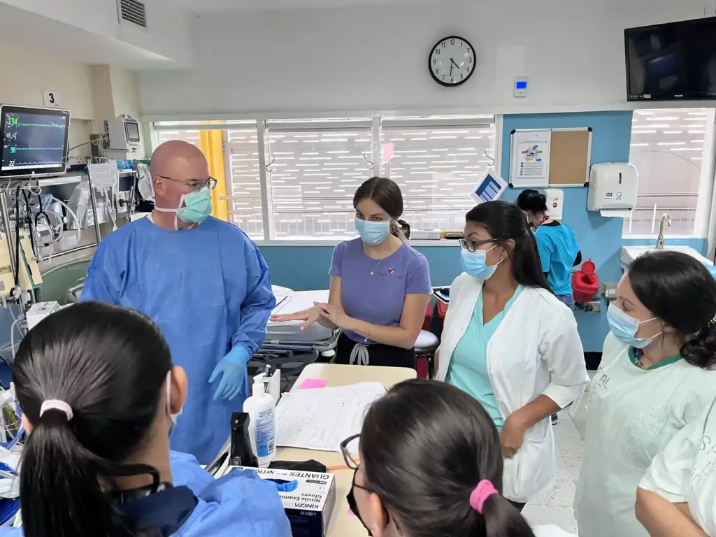 Grupo de profesionales médicos con mascarilla reunidos en una sala de hospital revisando documentos.