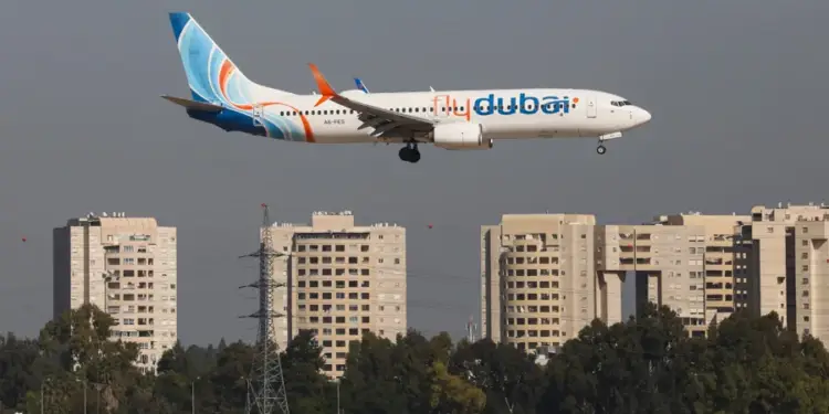 Avión comercial de la aerolínea Flydubai volando bajo durante la aproximación para aterrizar sobre una zona urbana con edificios.