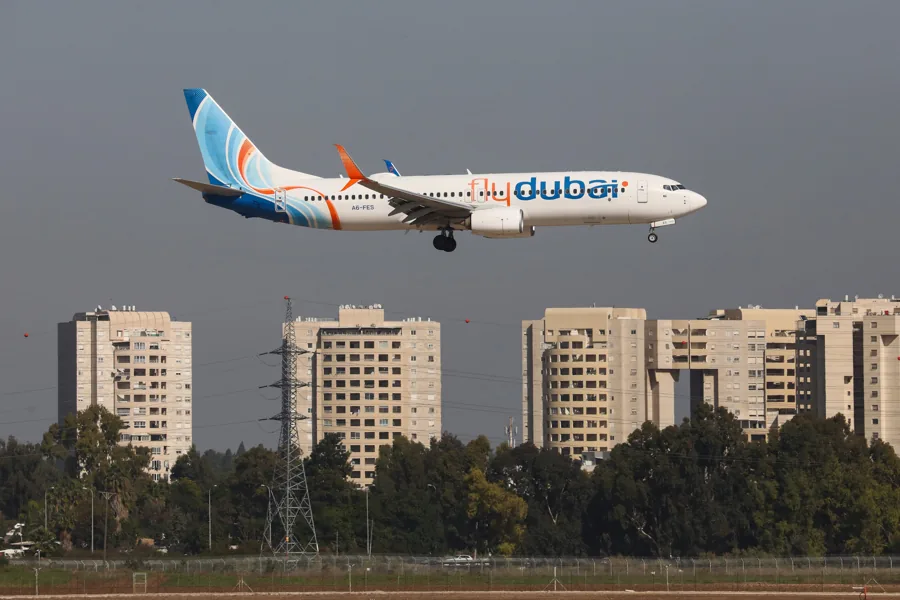 Avión comercial de la aerolínea Flydubai volando bajo durante la aproximación para aterrizar sobre una zona urbana con edificios.