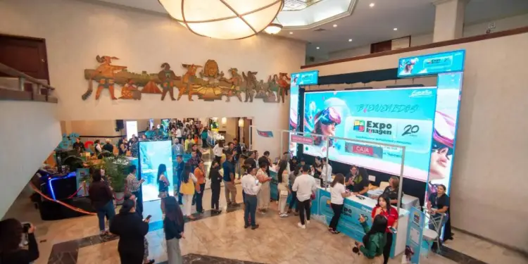 Vista superior de un concurrido vestíbulo de hotel con un mostrador de registro y pantallas LED para un evento de negocios.
