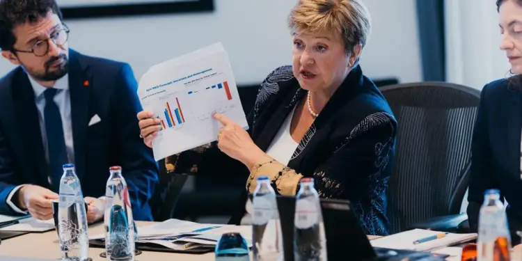 Mujer explicando un informe con gráficos de barras en una reunión de negocios con colegas en una sala de juntas.