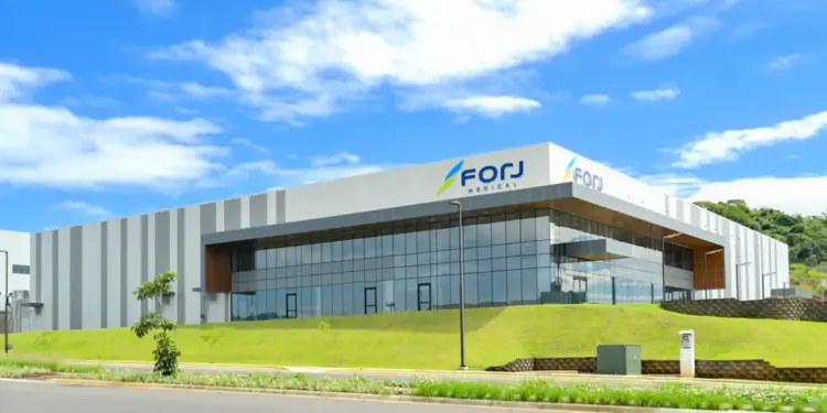 Fachada exterior de un edificio corporativo moderno con grandes ventanales de vidrio, paredes rayadas y el logotipo de Forj Medical.