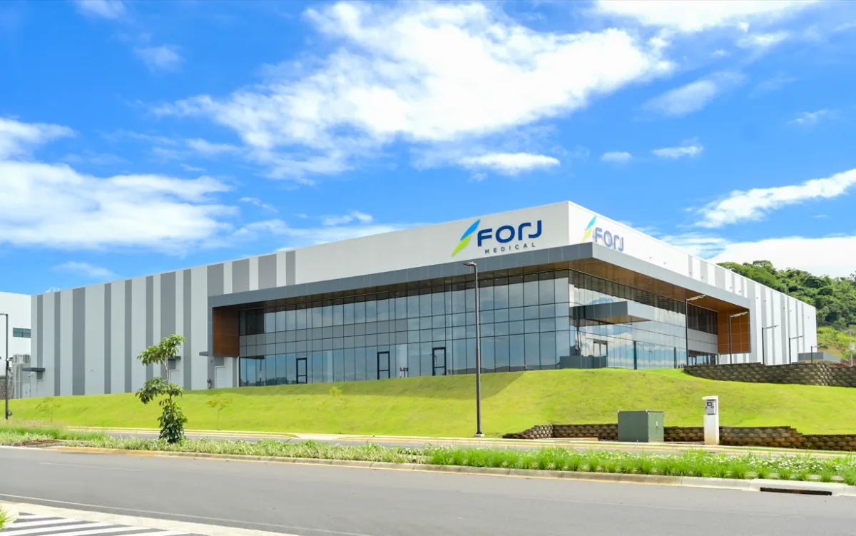Fachada exterior de un edificio corporativo moderno con grandes ventanales de vidrio, paredes rayadas y el logotipo de Forj Medical.
