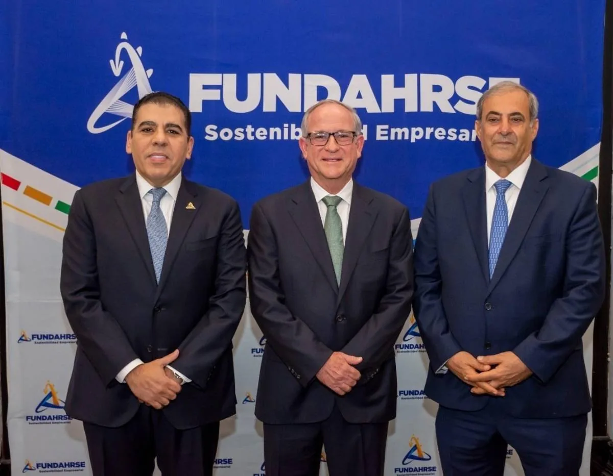 Tres hombres de negocios con traje y corbata posando frente a un fondo azul con el logotipo de FUNDAHRSE.