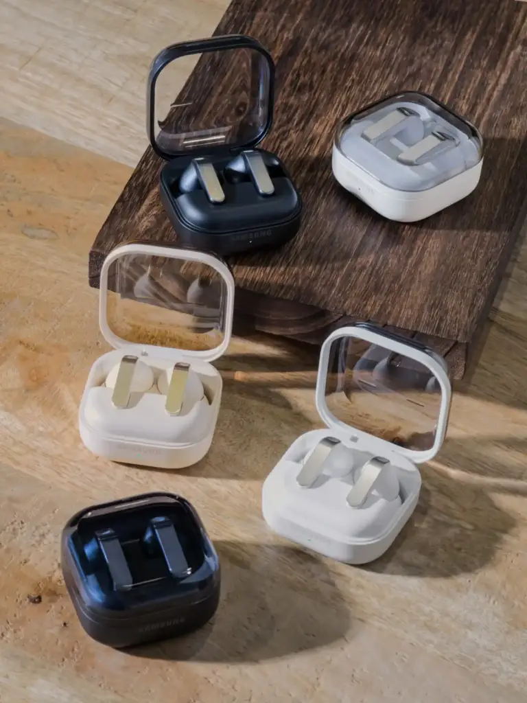 Varios estuches y auriculares inalámbricos de la marca Samsung en colores blanco y negro sobre superficie de madera.