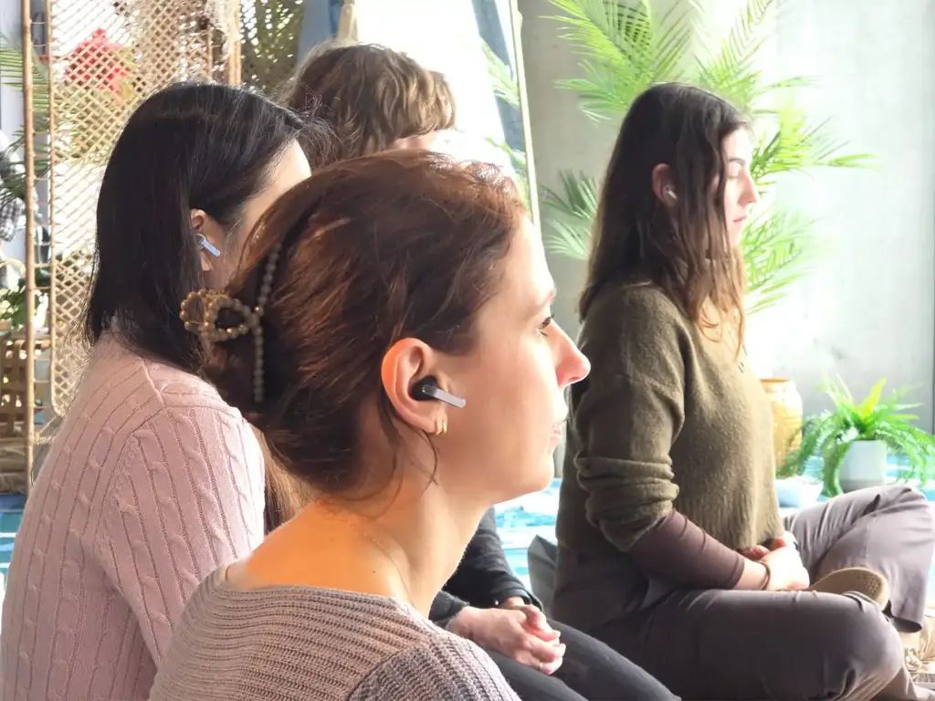 Grupo de mujeres sentadas en el suelo meditando y practicando mindfulness en un entorno de oficina iluminado.