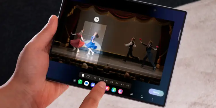 Manos sosteniendo una pantalla táctil plegable que muestra una interfaz de edición de video con bailarines en el escenario.