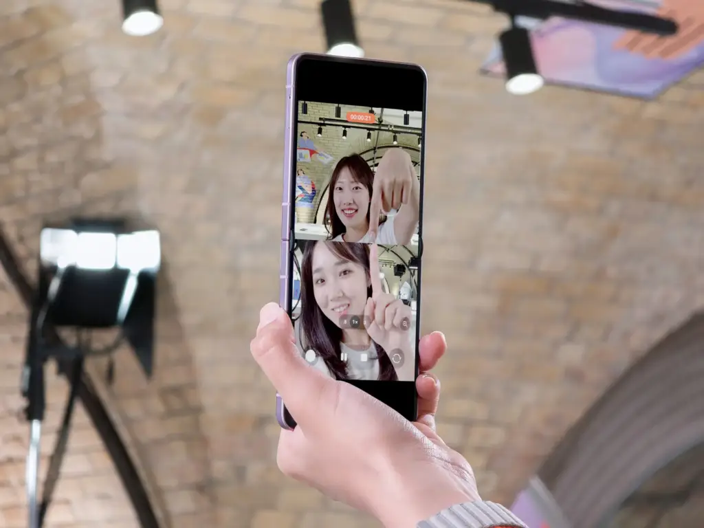 Una persona sostiene un teléfono inteligente plegable que muestra una videollamada con dos pantallas divididas.