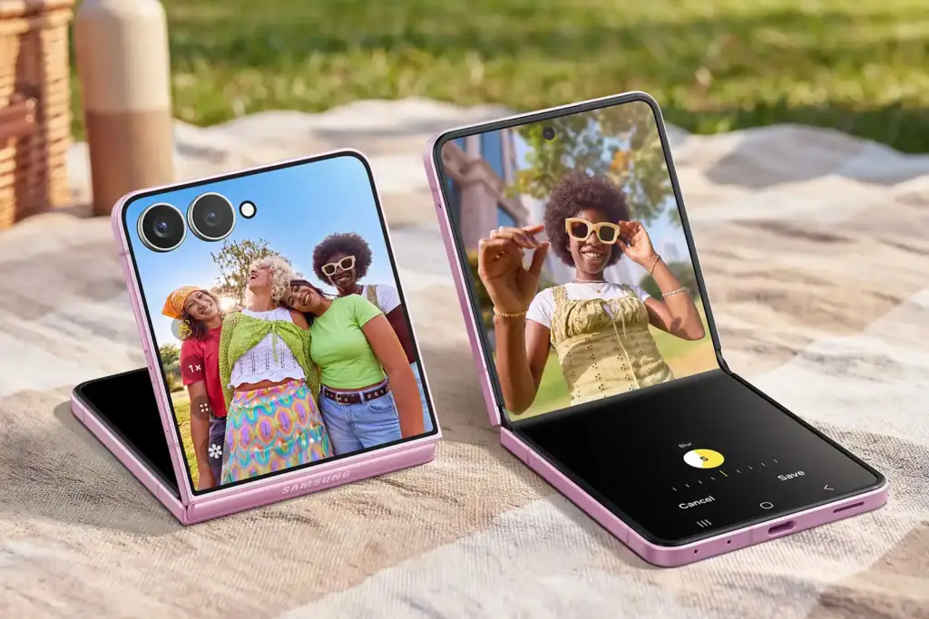 Dos teléfonos inteligentes plegables de color rosa colocados sobre una manta a cuadros en un entorno exterior con césped.