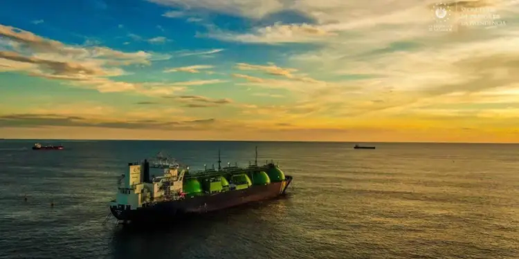 Gran buque tanque con contenedores esféricos verdes navegando en el mar abierto durante un atardecer dorado.