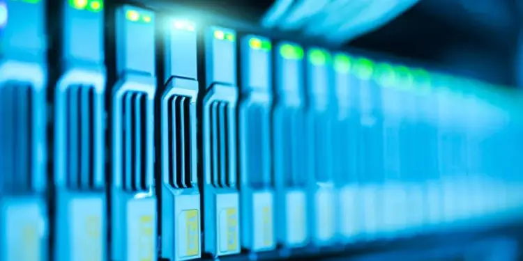 Primer plano de servidores informáticos en un centro de datos iluminados con luces LED verdes y azules.