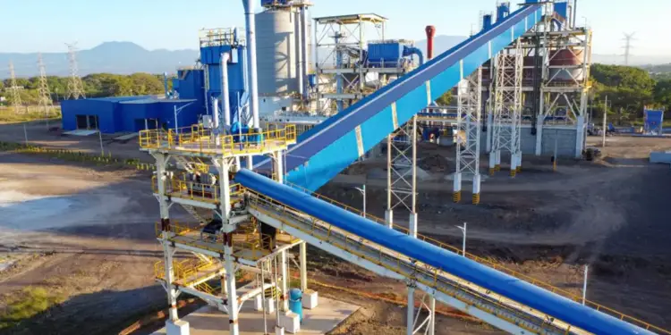 Vista aérea de una planta industrial moderna con estructuras metálicas azules y grandes cintas transportadoras.