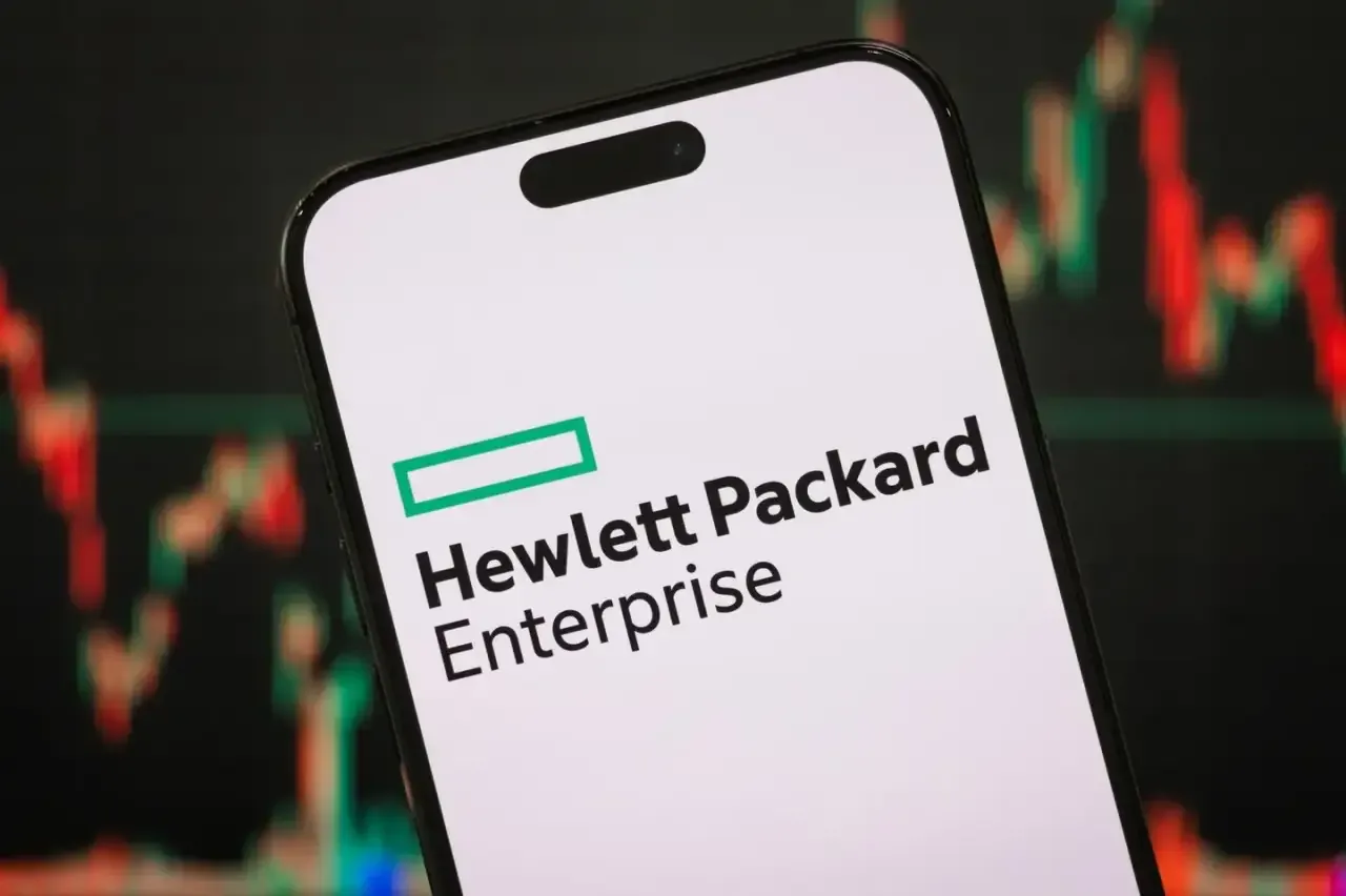 Logotipo de Hewlett Packard Enterprise en la pantalla de un smartphone con gráficos bursátiles al fondo.