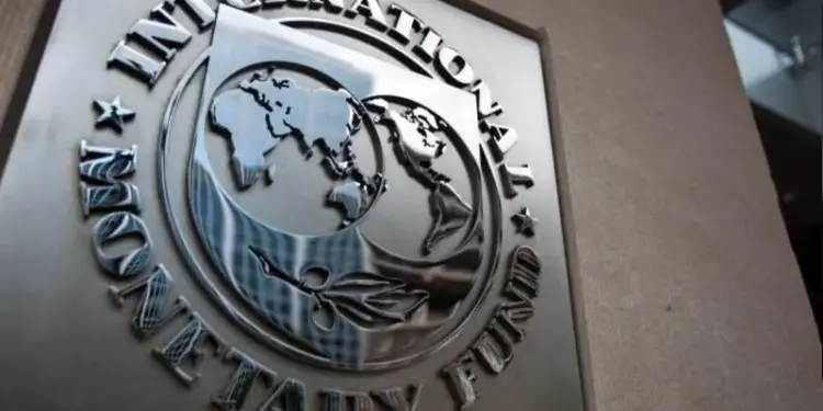Primer plano del emblema metálico del Fondo Monetario Internacional (FMI), que muestra un mapa del mundo estilizado y el texto 'International Monetary Fund'.