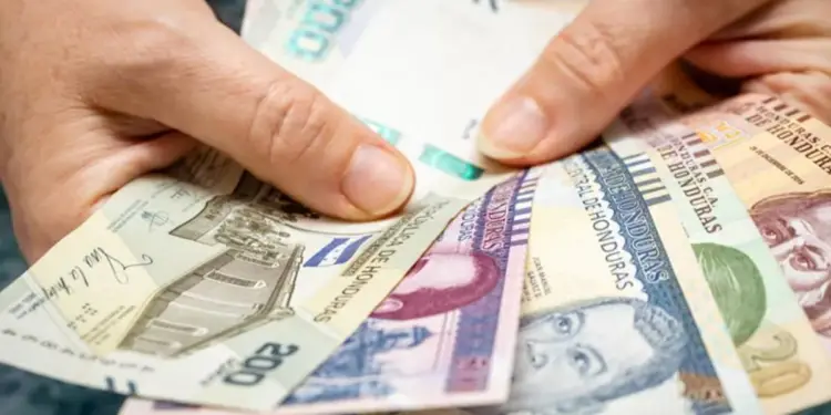 Manos sosteniendo y desplegando varios billetes en efectivo del Banco Central de Honduras de diferentes denominaciones.