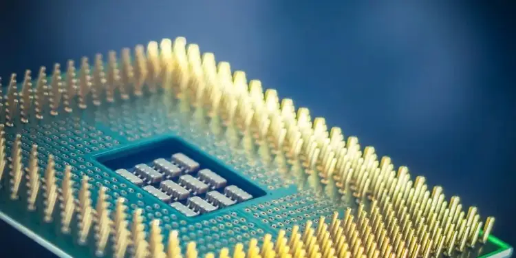 Primer plano de un procesador de computadora con pines dorados y un chip central visible, sobre un fondo azul oscuro. Representa la tecnología y la innovación.