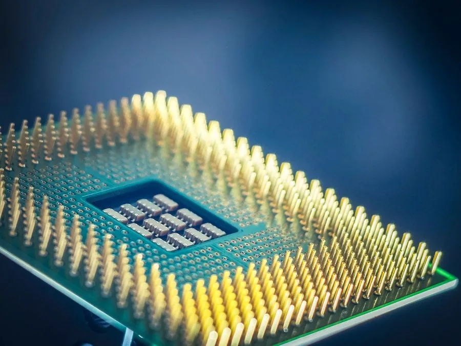Primer plano de un procesador de computadora con pines dorados y un chip central visible, sobre un fondo azul oscuro. Representa la tecnología y la innovación.