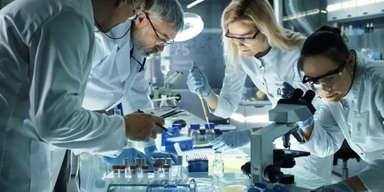 Equipo de científicos con batas blancas y gafas de seguridad trabajando juntos en un laboratorio moderno