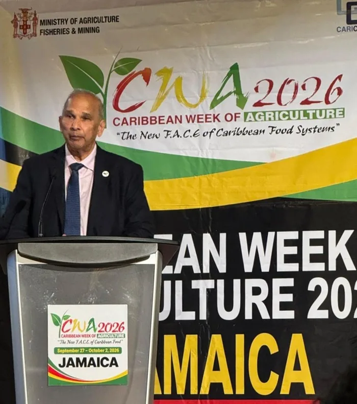 Hombre en traje hablando en podio durante la Semana de Agricultura del Caribe 2026 en Jamaica, con logo del Ministerio de Agricultura.