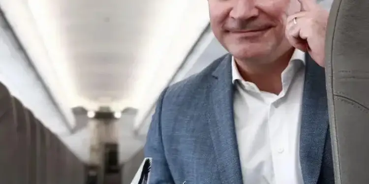 Hombre de negocios sonriente en cabina de avión, sosteniendo un modelo de JetSMART. Simboliza ideas y crecimiento en la aviación.