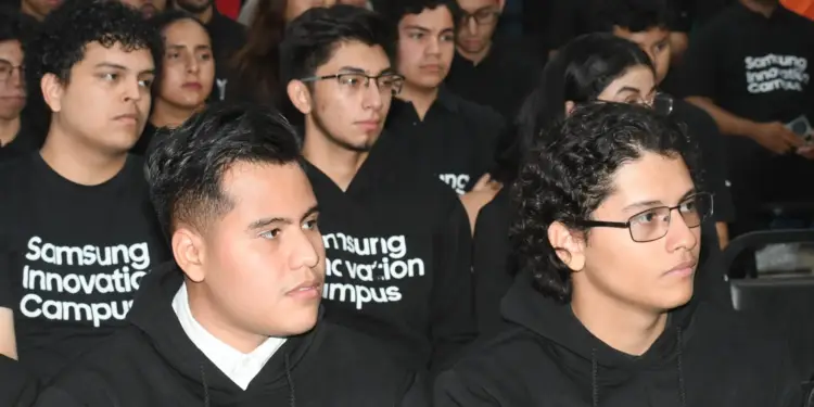 Grupo de jóvenes atentos con sudaderas negras en un evento tecnológico.