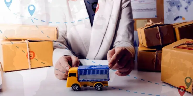 Persona de negocios junto a cajas de cartón y un camión de juguete con gráficos de logística superpuestos.