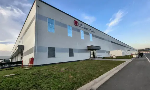 Edificio de LG Electronics, una estructura industrial moderna con paneles grises, ventanas reflectantes y un entorno ajardinado.