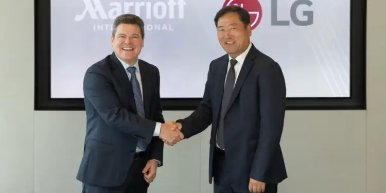 Dos ejecutivos estrechándose la mano frente a una pantalla con los logos de Marriott International y LG.