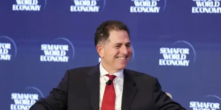 Hombre de negocios sonriente con traje oscuro y corbata roja, sentado frente a un fondo azul con el logo 'Semafor World Economy'.