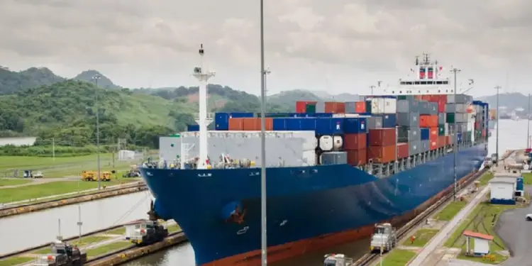 Gran buque portacontenedores azul transitando por una esclusa de canal para el transporte de mercancías.