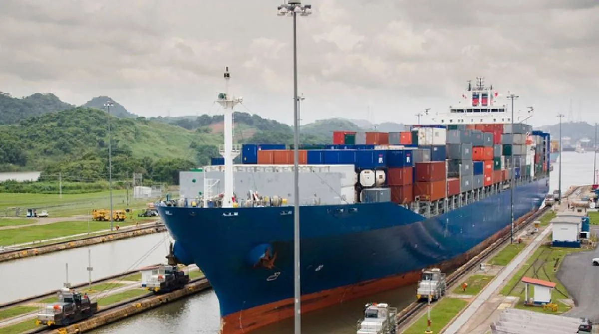 Gran buque portacontenedores azul transitando por una esclusa de canal para el transporte de mercancías.