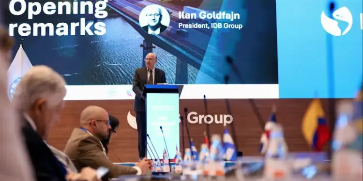 Ilan Goldfajn, presidente del Grupo IDB, da un discurso en una conferencia. Detrás, una pantalla muestra un puente y la audiencia escucha.