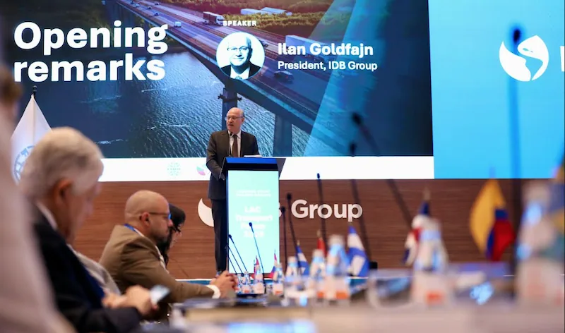 Ilan Goldfajn, presidente del Grupo IDB, da un discurso en una conferencia. Detrás, una pantalla muestra un puente y la audiencia escucha.